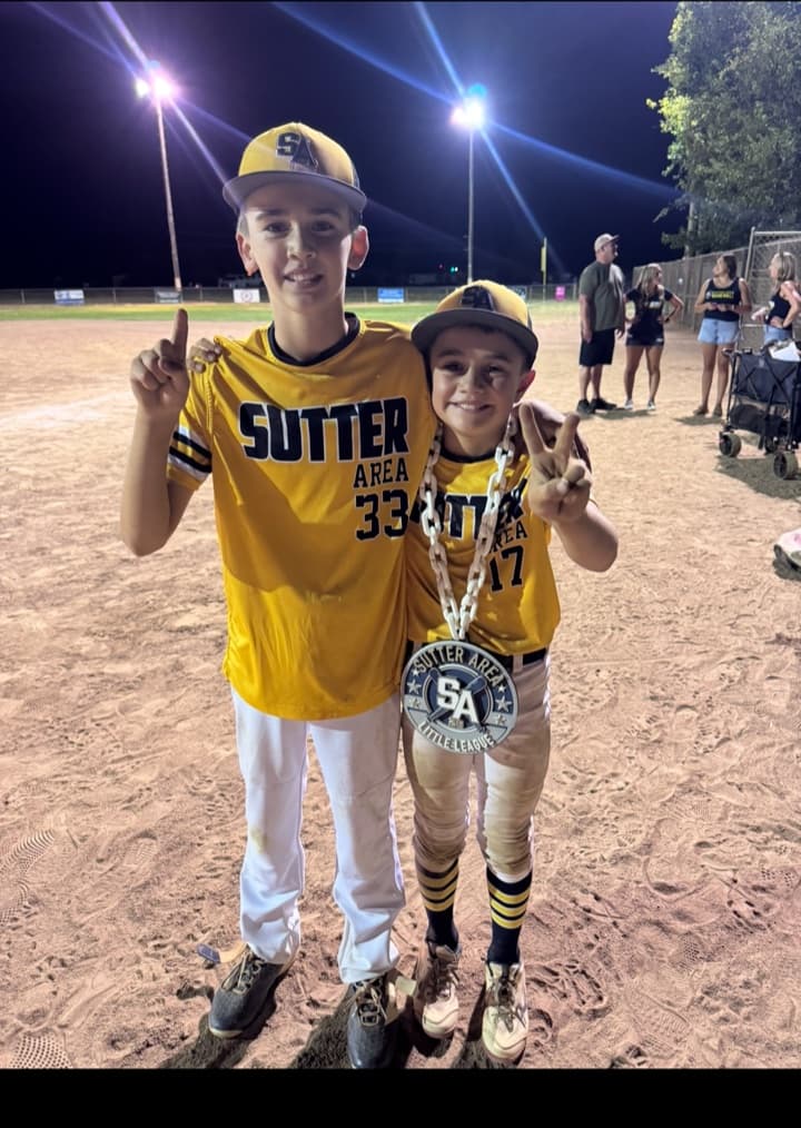 Two youth baseball players celebrating on the field with a round custom team chain