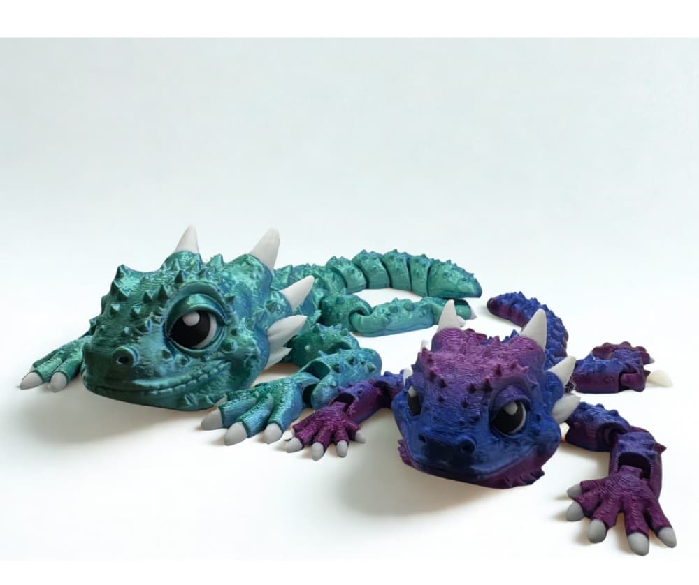 Two 3D-printed articulated dragon figurines in teal and purple