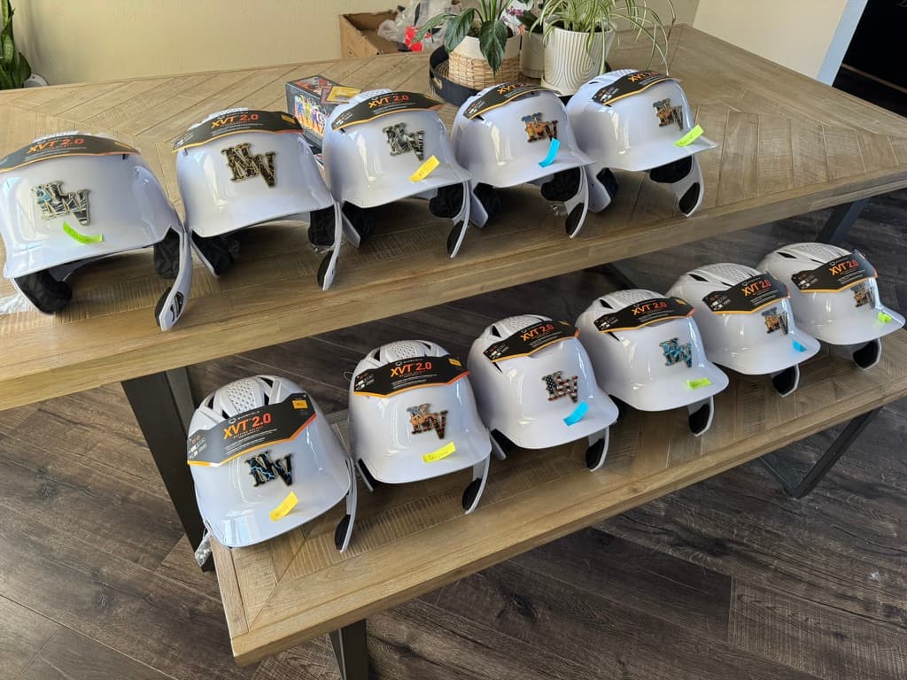 Team of white batting helmets displaying raised NV logo decals in different artwork designs