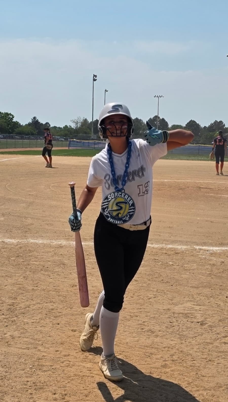 Sorcerer softball player on the field wearing the team chain and holding a bat