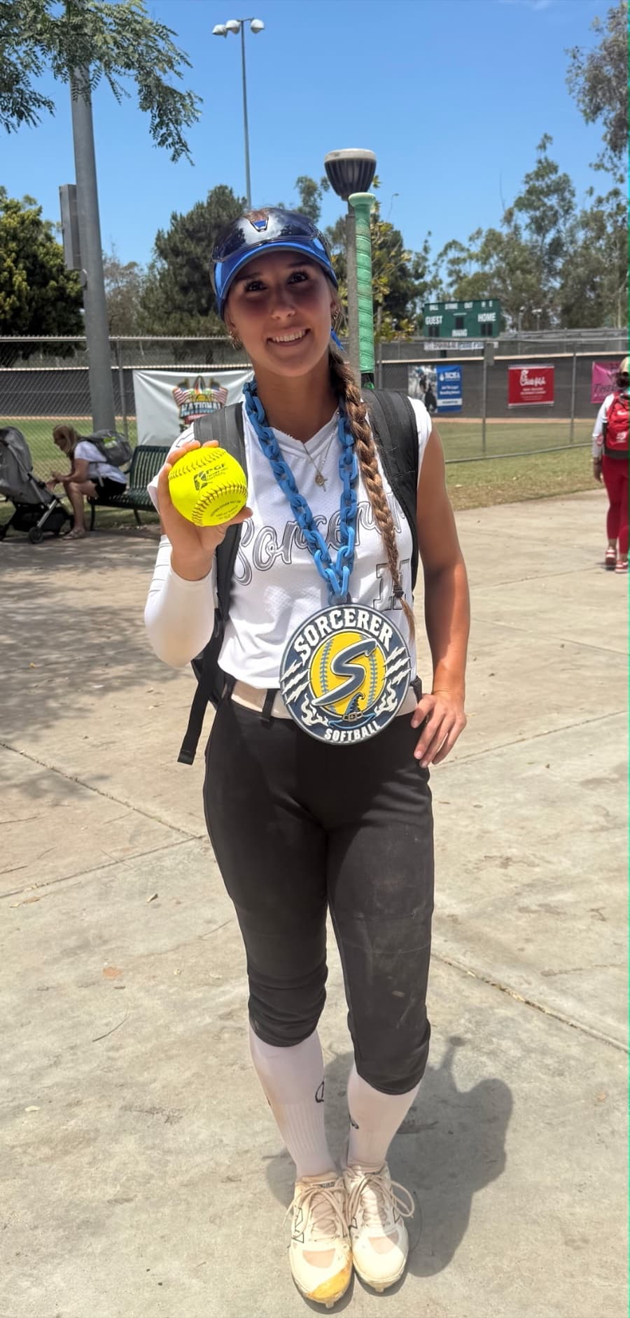 Sorcerer softball player holding a game ball while wearing her custom team chain