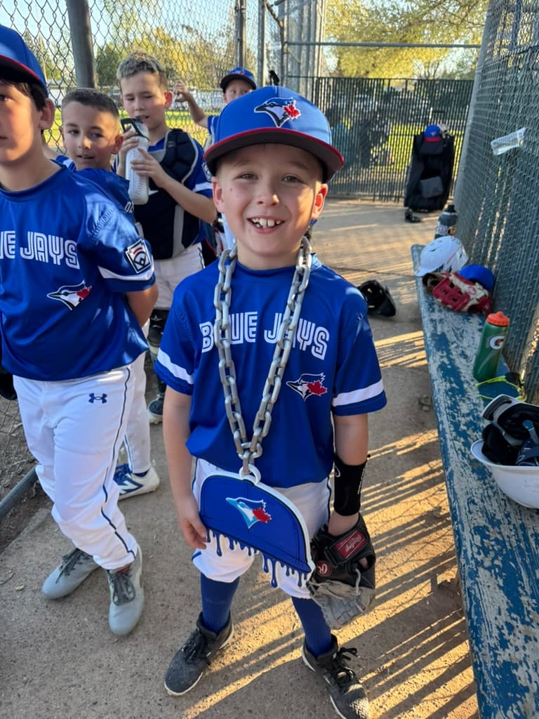 Young Blue Jays baseball player wearing a custom drip-cap hype chain