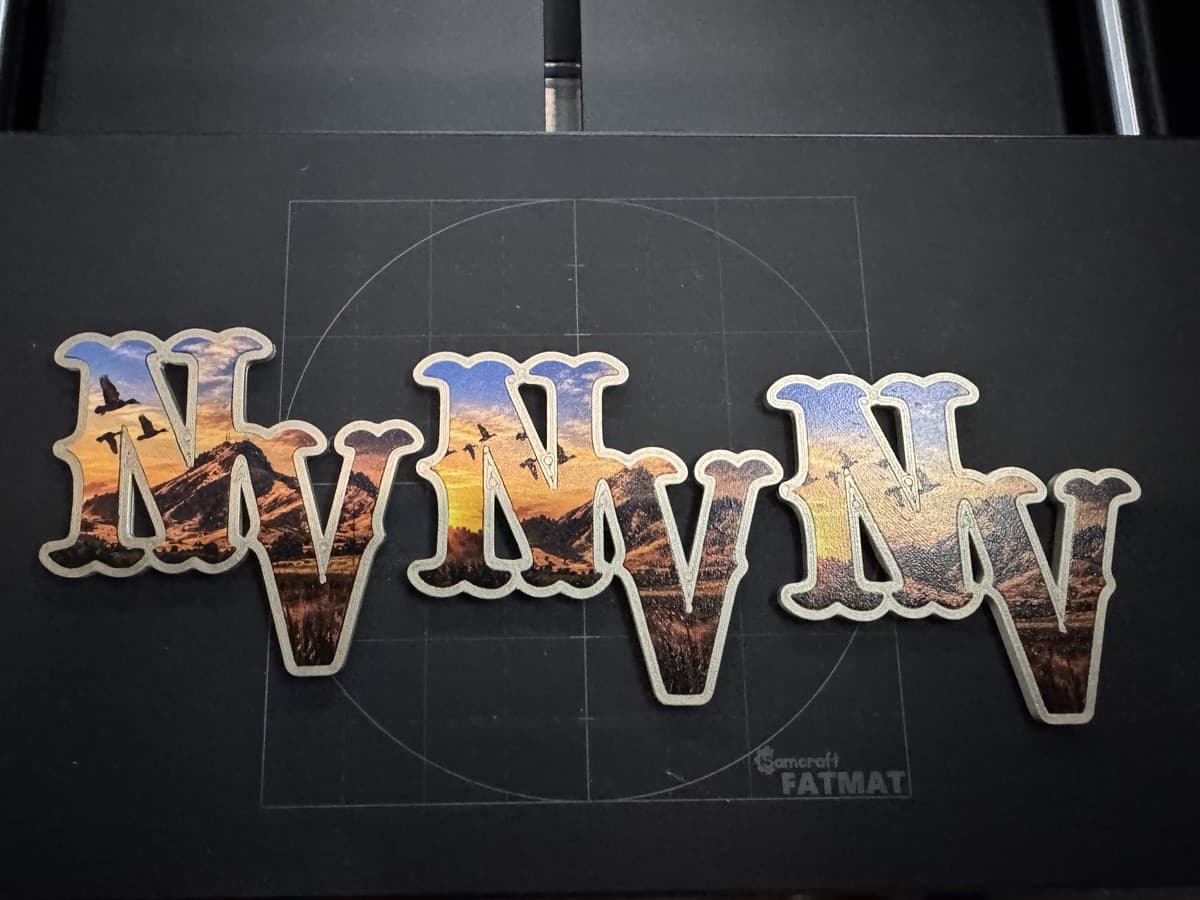 Three NV helmet decals with multicolor artwork on a cutting mat
