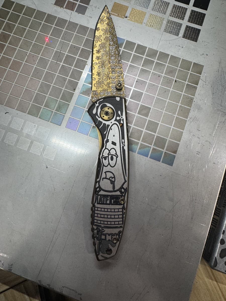 Open knife showing engraved character handle and patterned blade