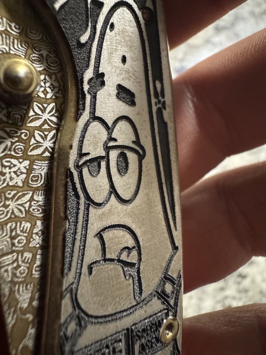 Close view of engraved character artwork on the same knife handle