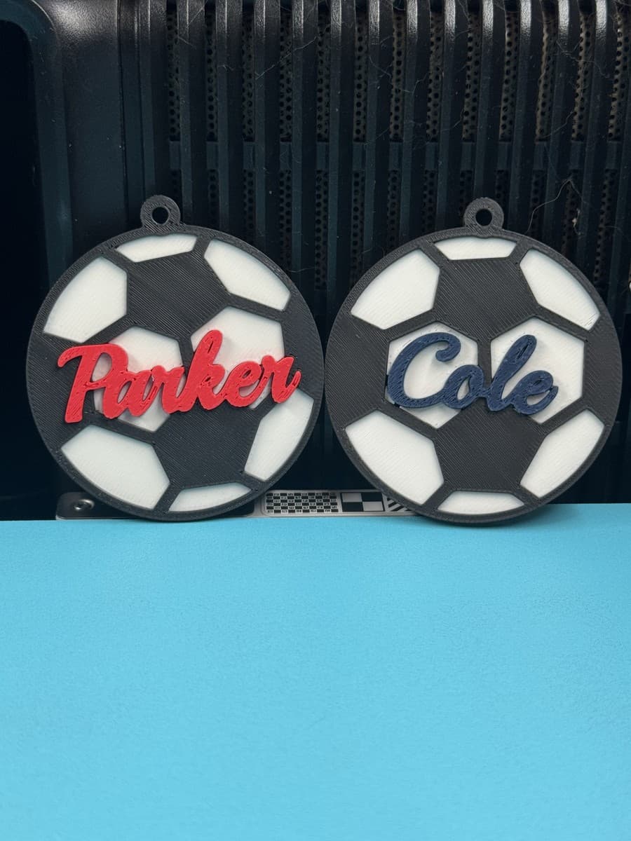 Two personalized soccer-ball bag tags with Parker and Cole lettering