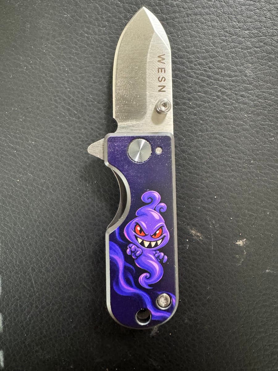 Completed TD3D decorative UV print of a purple character on a knife handle, shown with the blade open