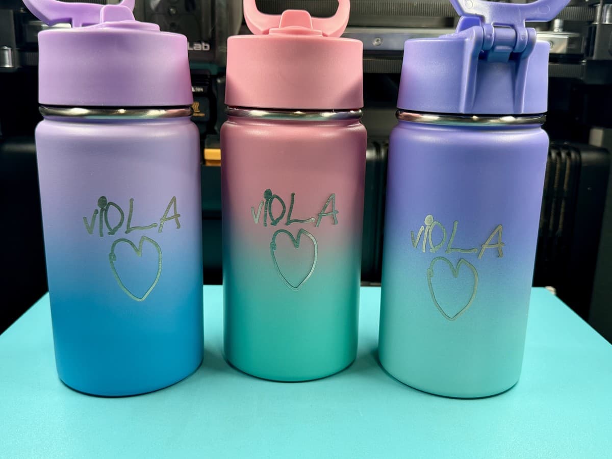 Three pastel water bottles engraved with a child’s handwriting and heart
